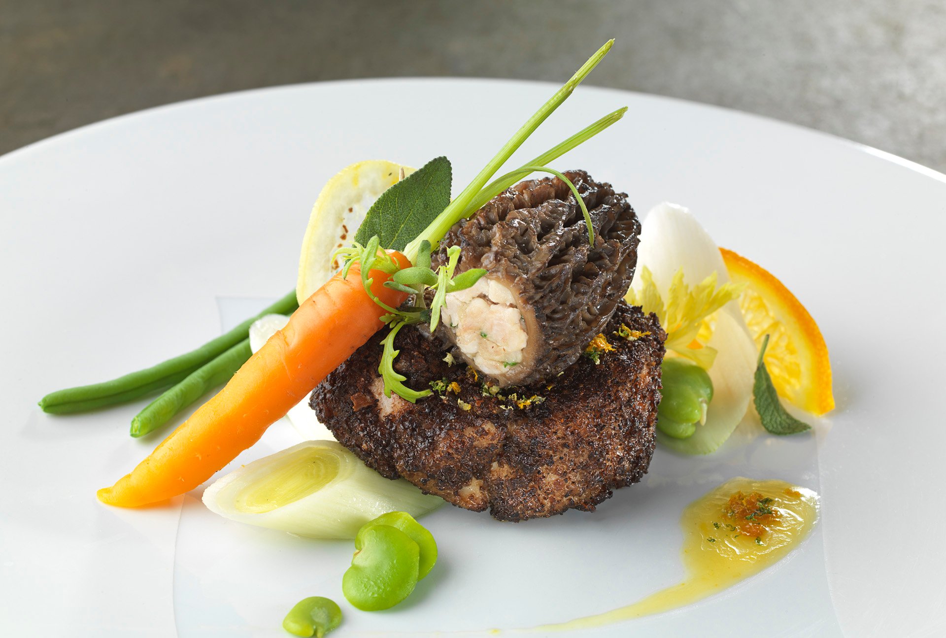 Fantasy of veal sweetbreads coated in morel mushrooms, fresh vegetables with citrus butter